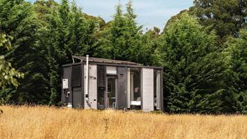A small, single-story cabin with a sloped roof, a visible chimney, and a door leading to an interior space.