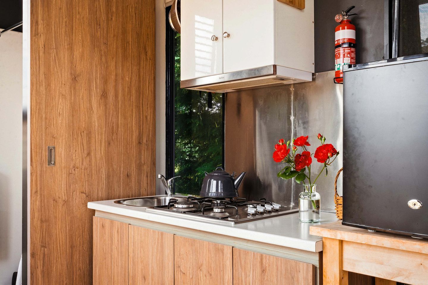 A compact kitchen with a gas stove, a sink, and a stainless steel refrigerator.