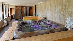 A spa area with a hot tub, wooden benches, and a wooden wall.