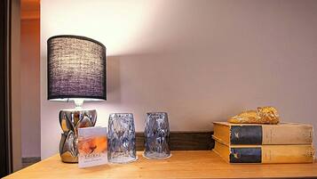 Uma mesa com uma lâmpada, três vasos de vidro, um livro e um objeto decorativo.