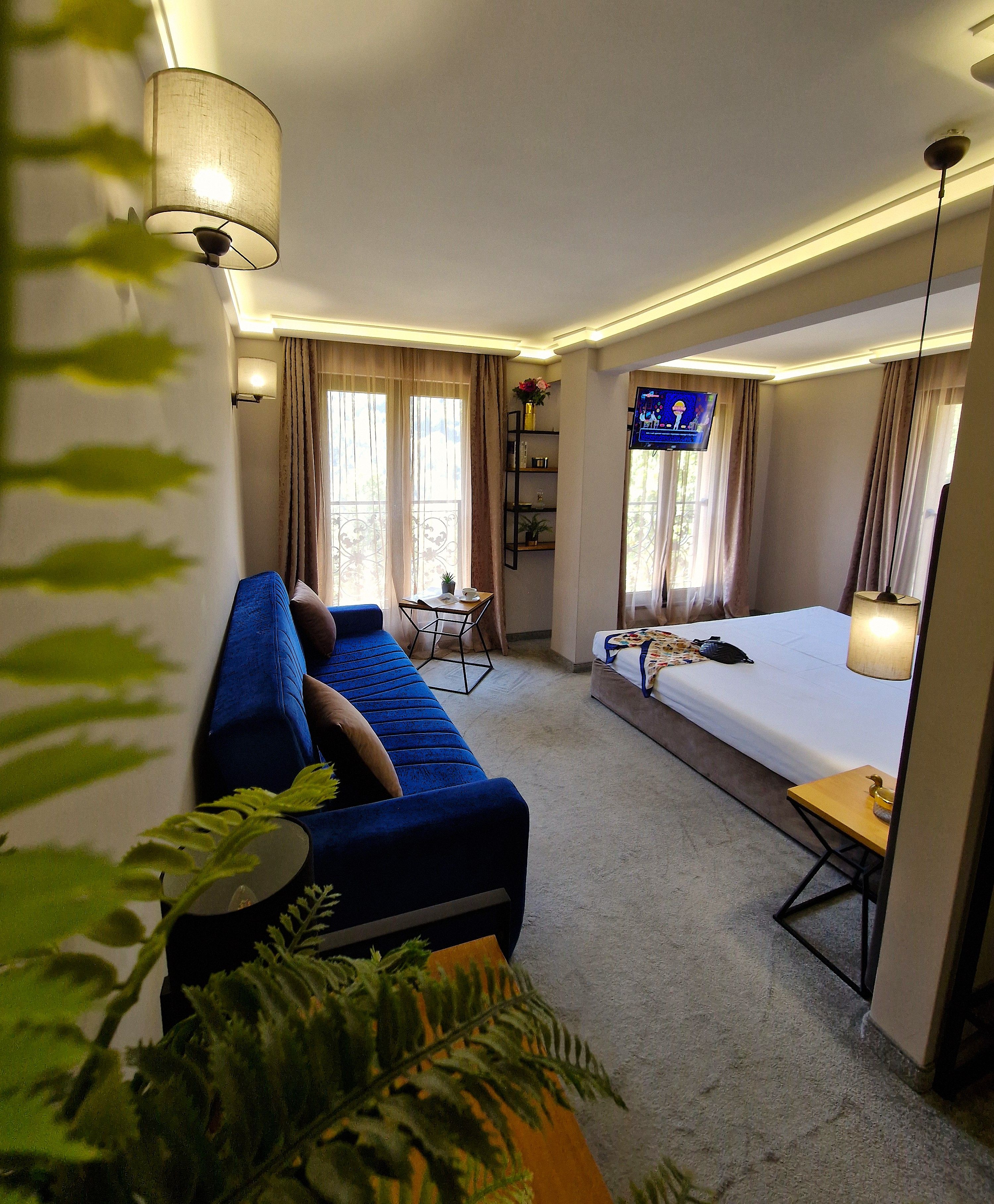 Una habitación de hotel con un sofá azul, una cama, un televisor y una mesita.