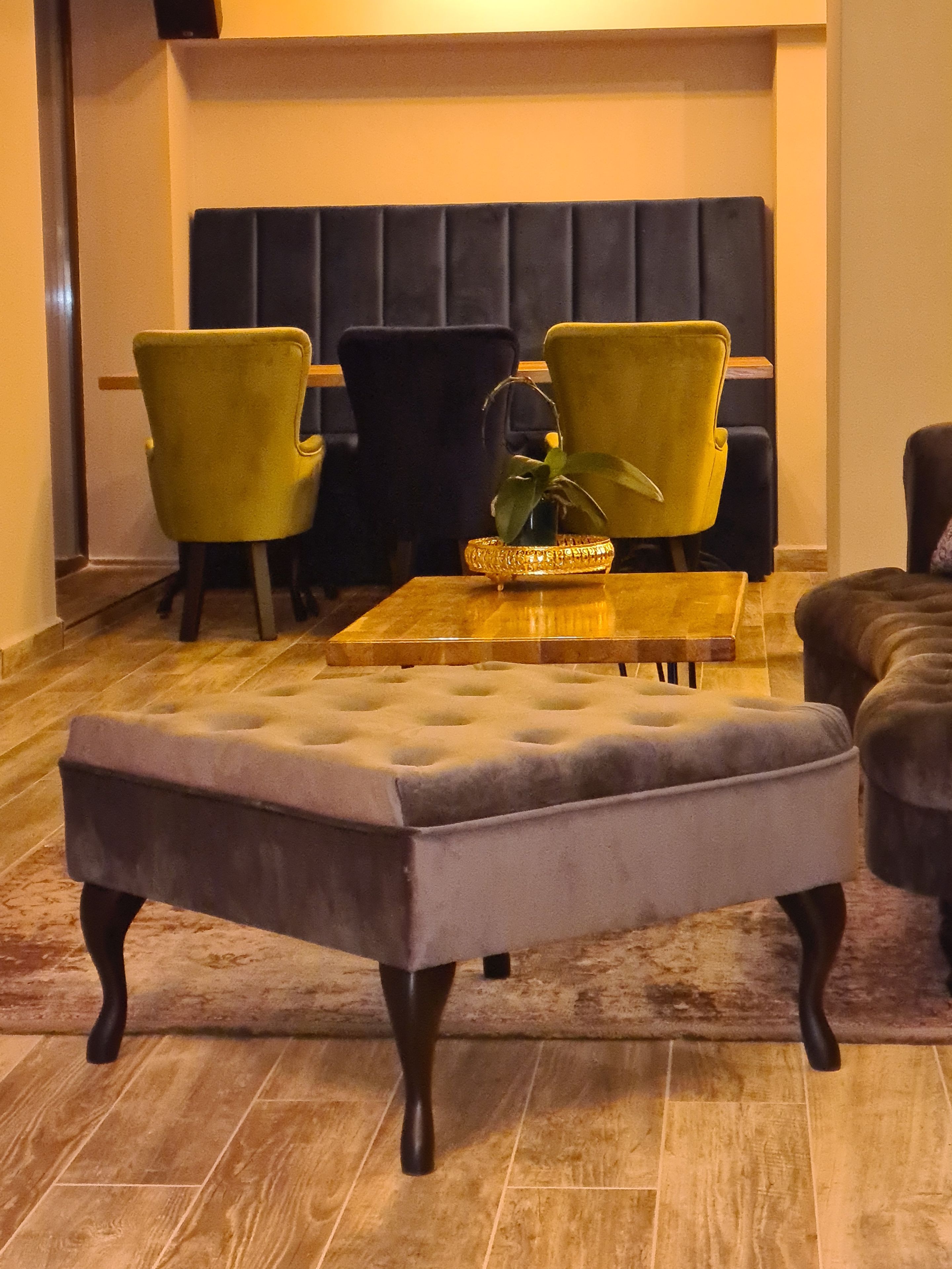Eine Sitzecke mit einem gesteppten Ottomanen, zwei Sesseln und einem Couchtisch.