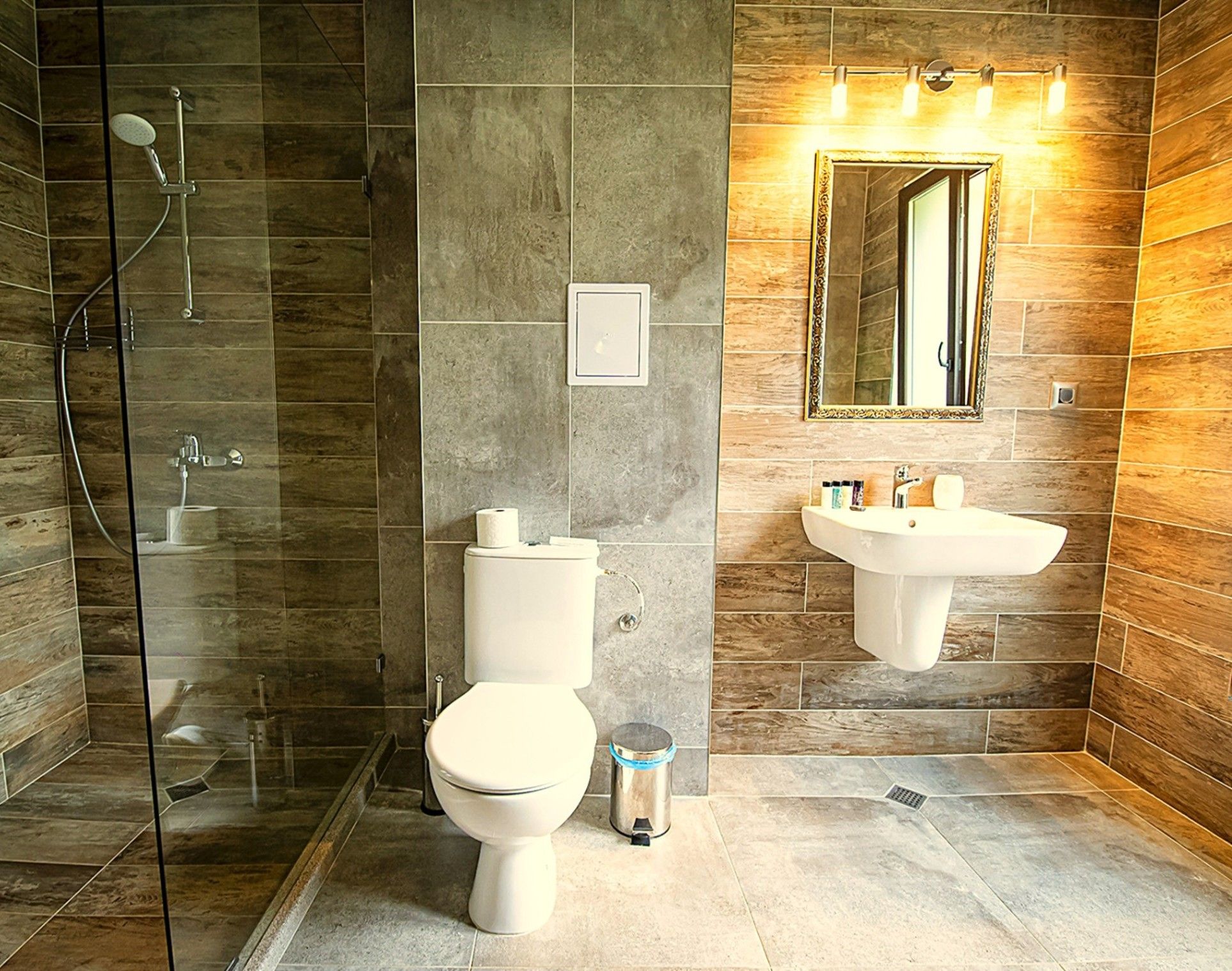 Une salle de bain moderne avec une douche à parois de verre, des toilettes et un lavabo surmonté d’un miroir.