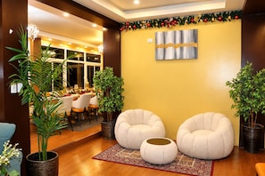 A modern interior with two round seating areas, a dining table with chairs, and a decorative wall piece.