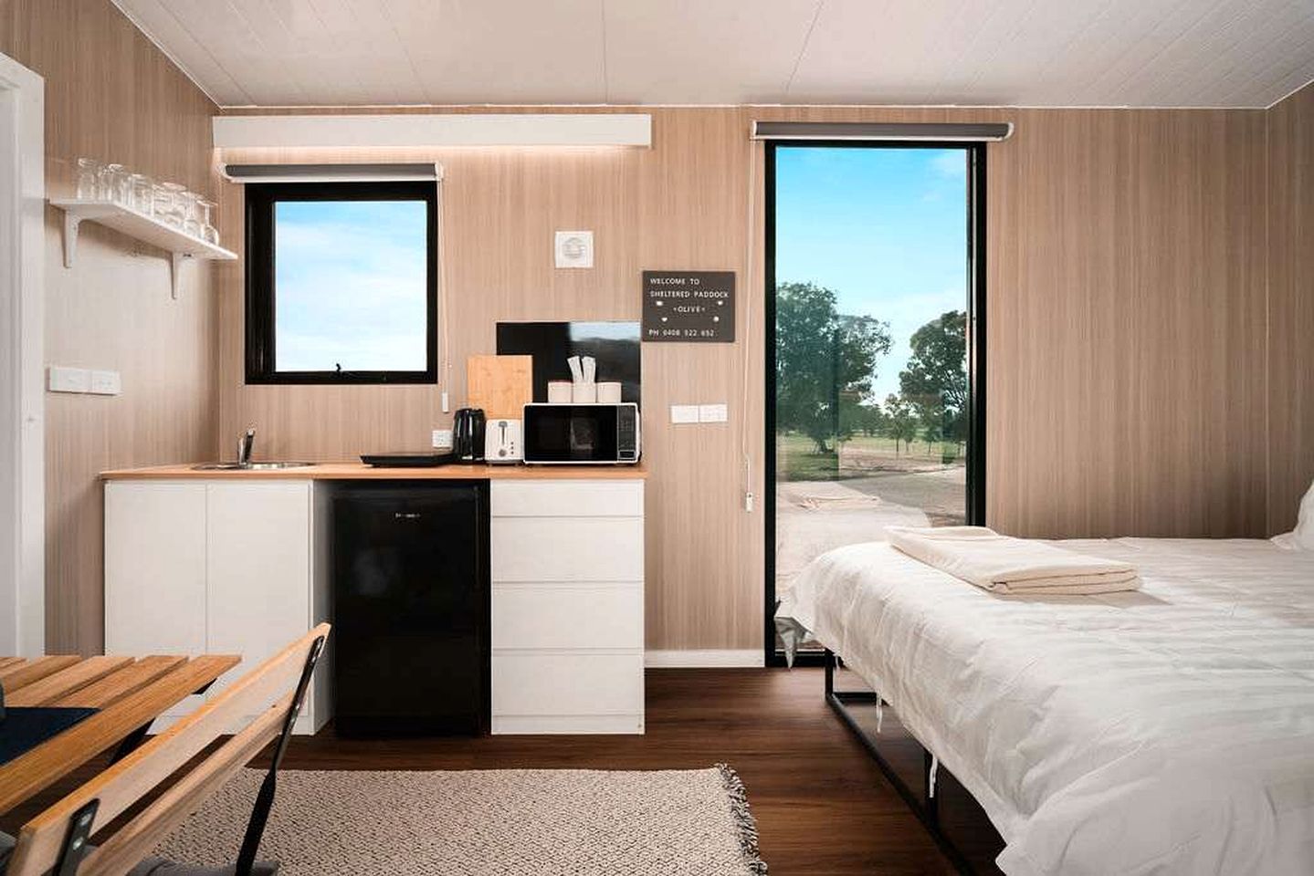 Una habitación funcional con kitchenette, cama y un amplio ventanal con vistas.