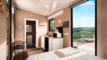 A modern bedroom with a bed, a desk, and a view of the outdoors.