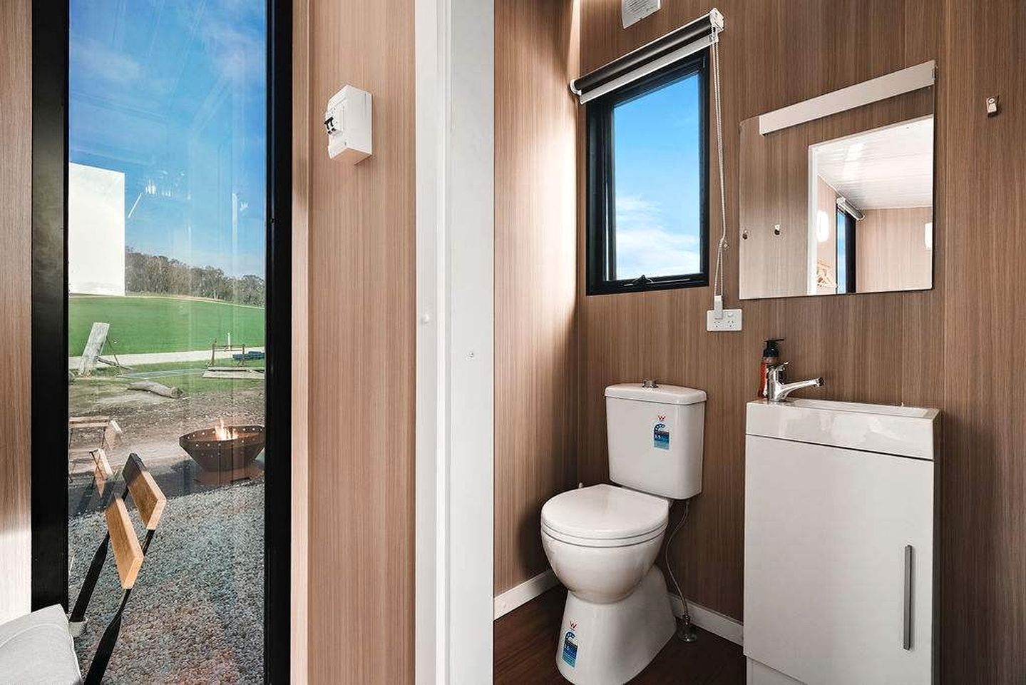 Ein modernes Badezimmer mit Toilette, Waschbecken und Fenster.