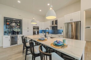 A modern kitchen with white cabinetry, stainless steel appliances, and a central island with seating. - New to the vacation rental, 4bed/3bath, hot tub and heated pool (Cape Coral)