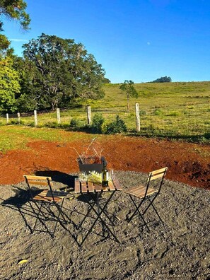 An outdoor seating area with a table and chairs, surrounded by a fenced field and trees. - Tiny House Retreat with Scenic Country Views in Numulgi, Australia (Numulgi)