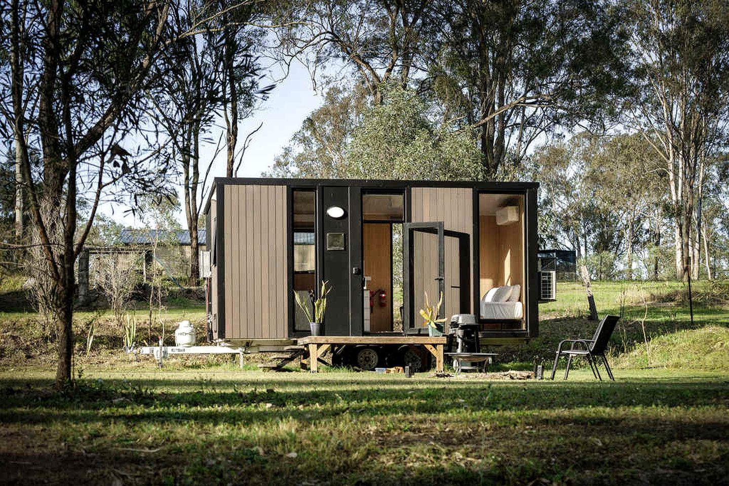 A small cabin with a sliding door, a dining table, and a chair outside.