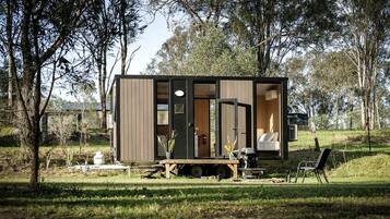 A small cabin with a sliding door, a dining table, and a chair outside.