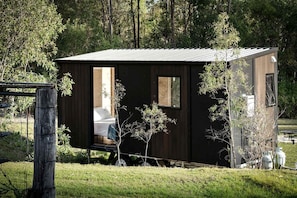 A small, dark-colored cabin with a single visible room, a door, and a window.