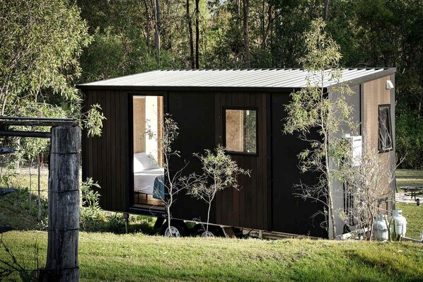 Una cabaña pequeña y oscura con una sola habitación visible, una puerta y una ventana.