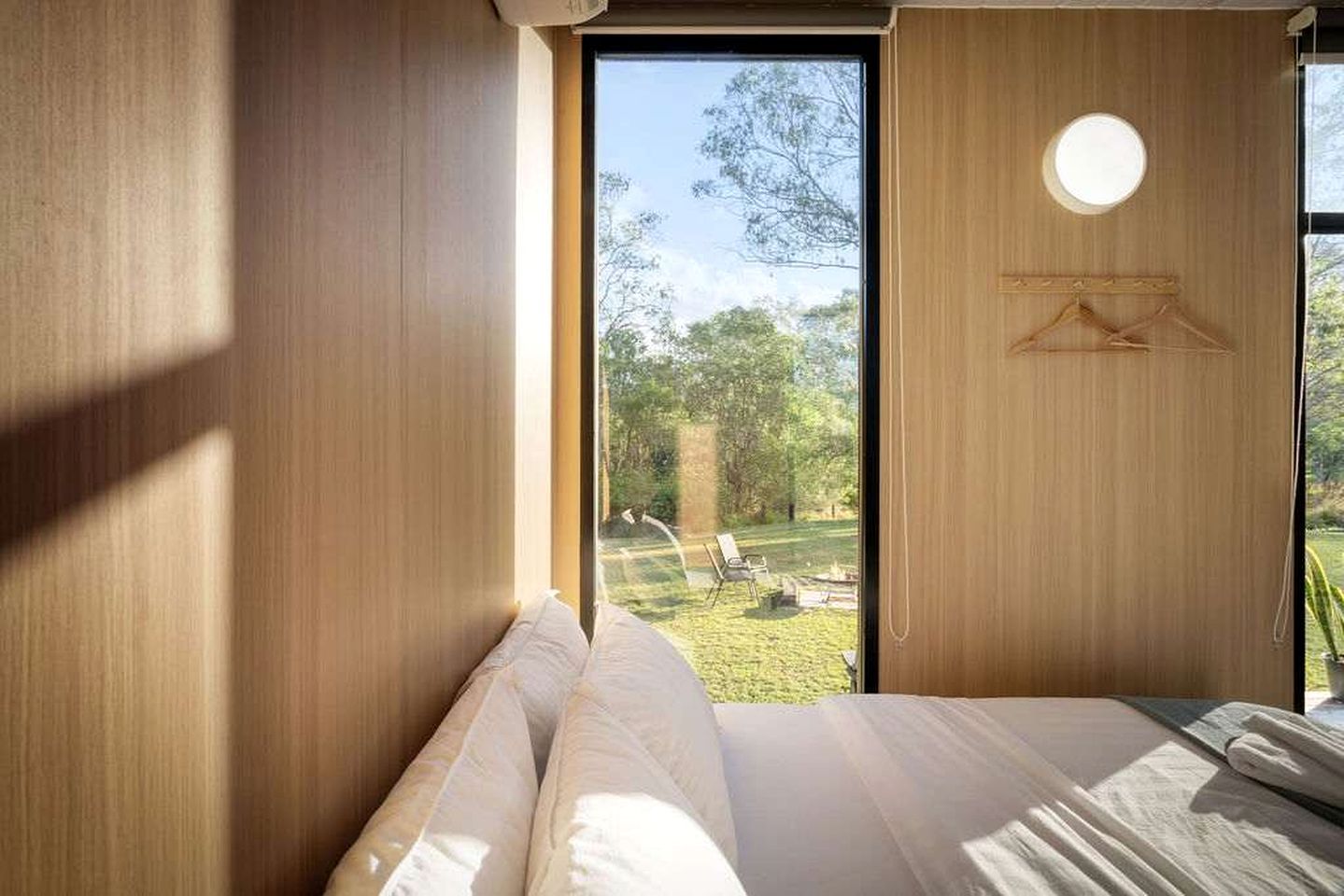 Een kamer met een bed, een raam en uitzicht op een buitenruimte.