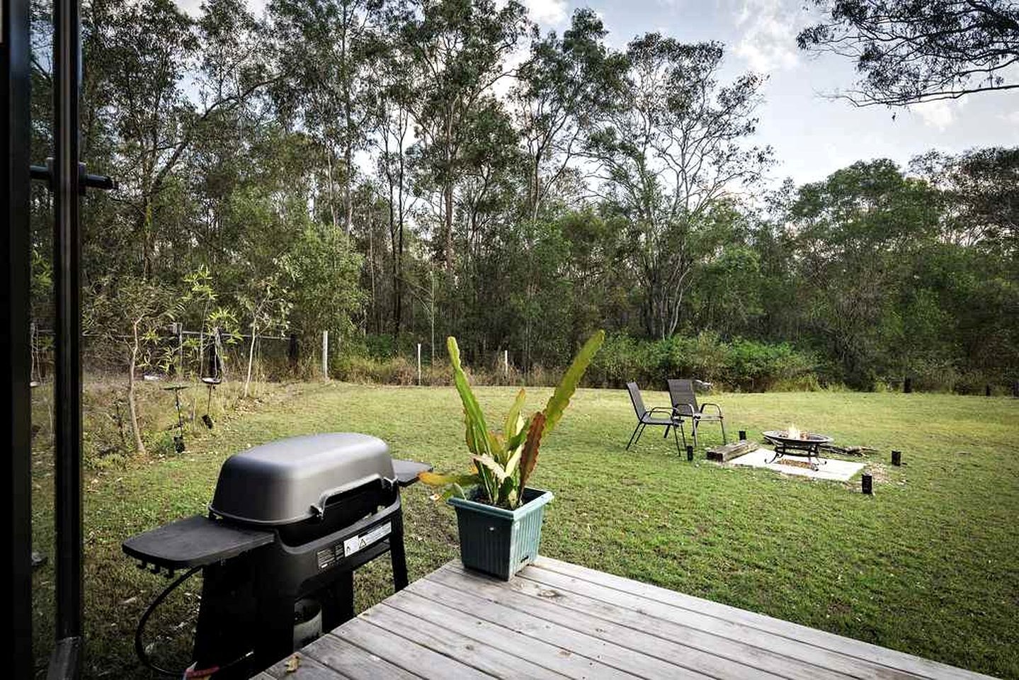 A backyard with a barbecue grill, a table, chairs, and a fire pit.