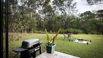 A backyard with a barbecue grill, a table, chairs, and a fire pit.