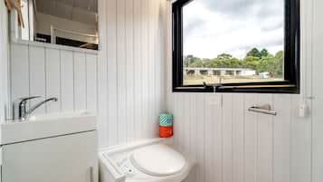 Un baño con un lavamanos blanco, un espejo y una ventana.