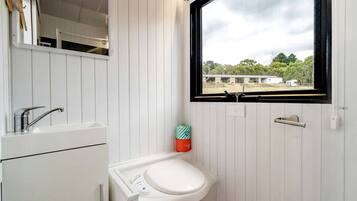 A bathroom with a white sink, a mirror, and a window.