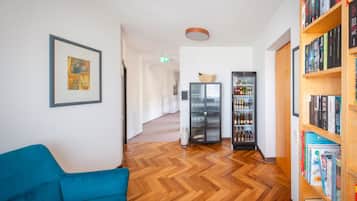 Ein Flur mit einem blauen Sofa, einem Bücherregal und einem Kühlschrank.