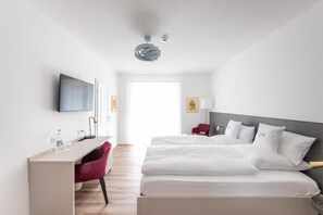 A hotel room with a bed, a desk, a chair, a television, and a window. - Hotel Magnolie GmbH (Laufenburg)
