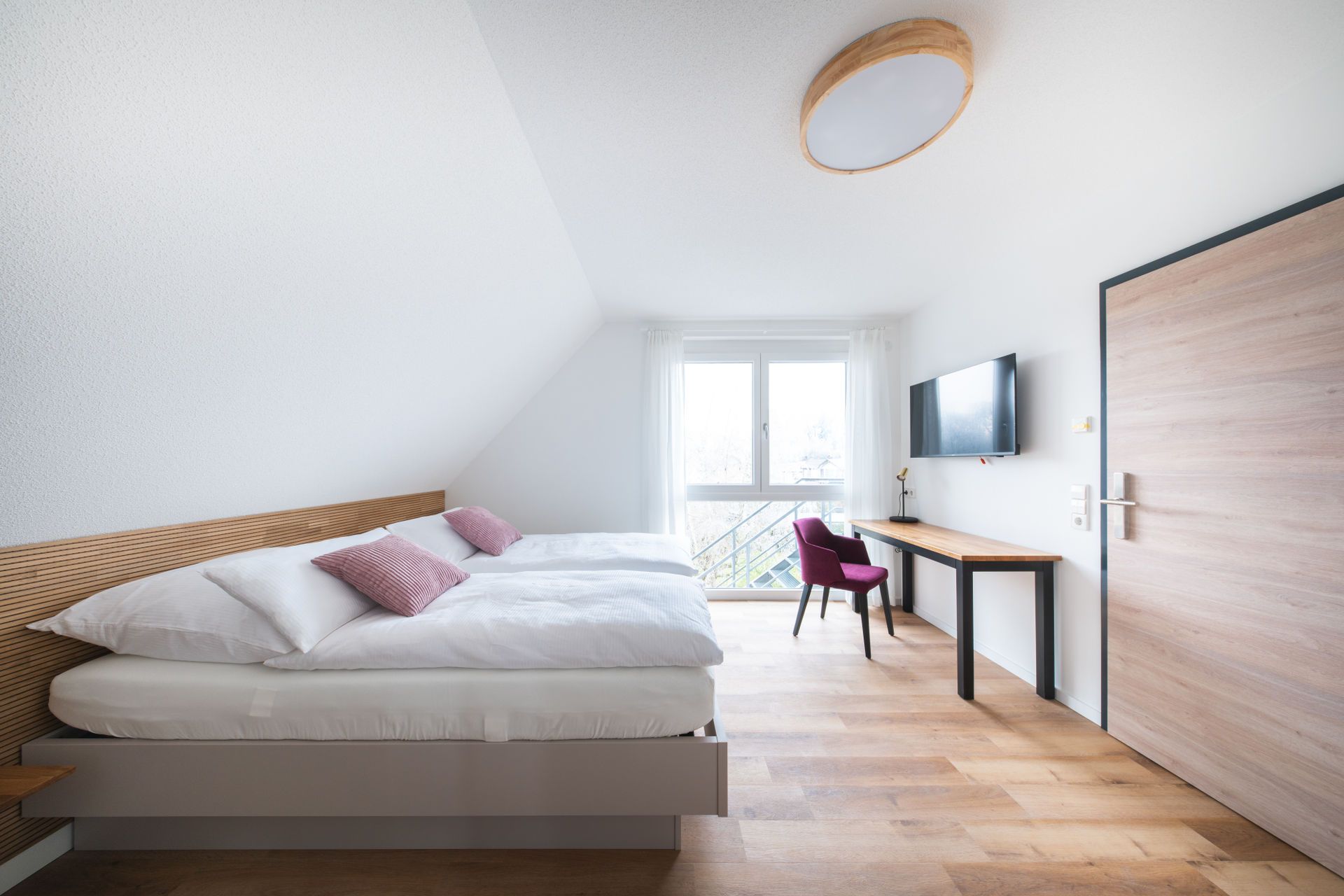 A modern bedroom with a loft bed, a desk, and a TV.