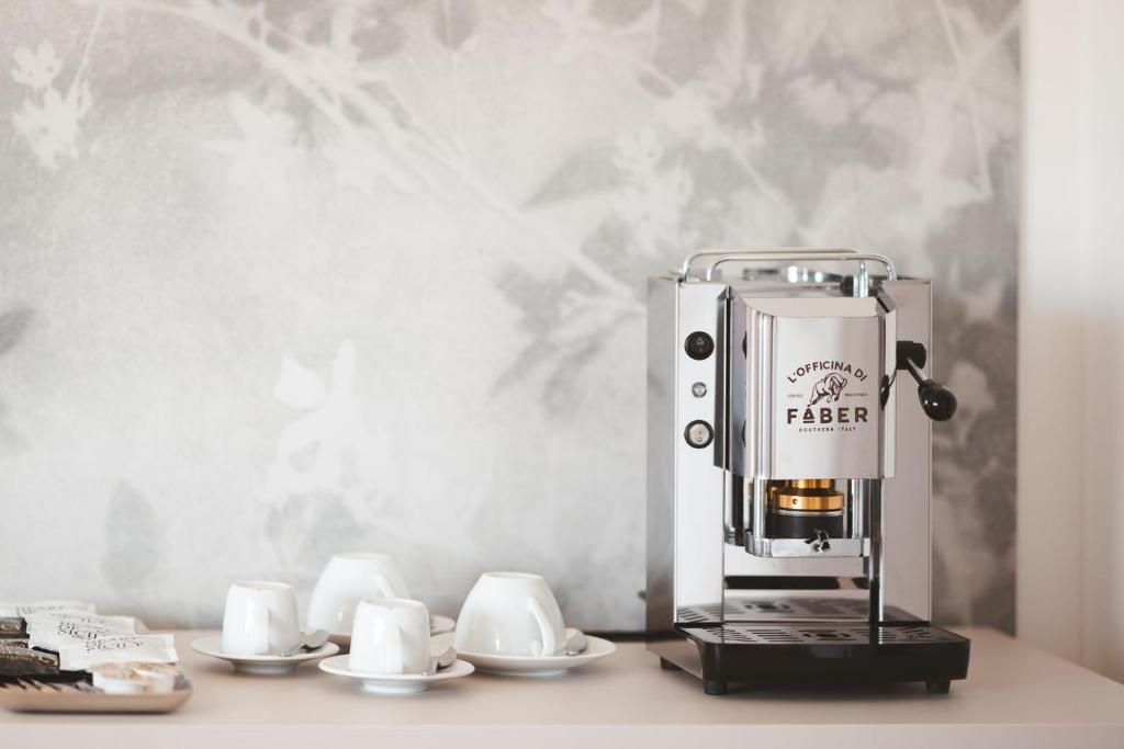 Una cafetera con una etiqueta de marca visible, acompañada por tazas y platillos blancos sobre una mesa.