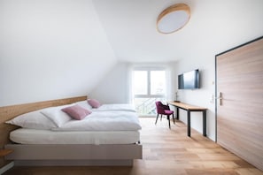 A modern bedroom with a bed, a desk, a chair, and a television. - Hotel Magnolie GmbH (Laufenburg)