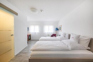 A bedroom with two beds, a desk, and a chair. - Hotel Magnolie GmbH (Laufenburg)