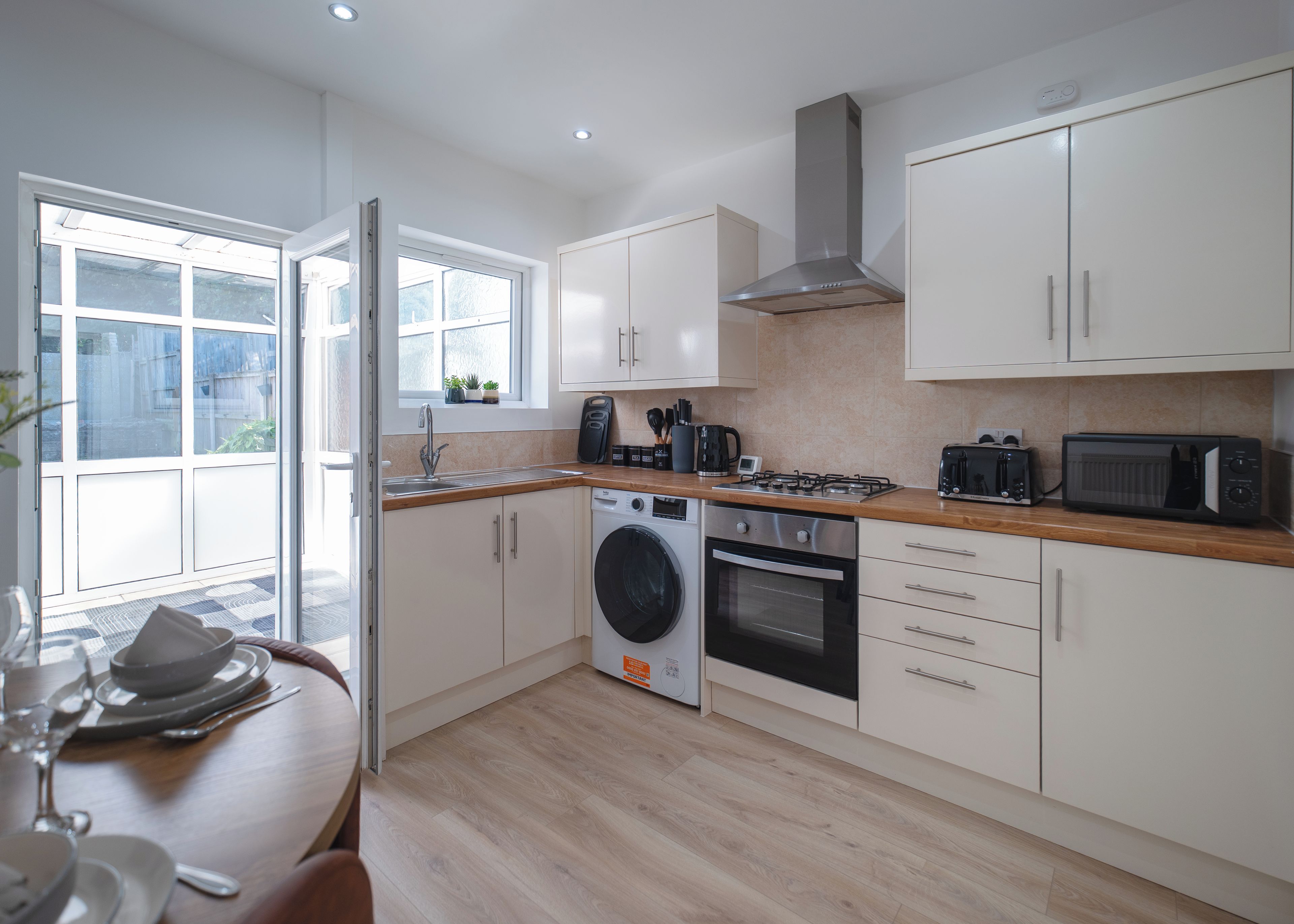 A modern kitchen with a washing machine, oven, and microwave.