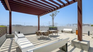A rooftop terrace with a pergola, outdoor seating, and a view of the cityscape. - Modern Layout Studio,Smooth Drive from Nad Al Sheba Stadium & Meydan Racecourse (Dubai)