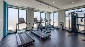 A gym with treadmills, elliptical machines, and a weight machine. - Modern Layout Studio,Smooth Drive from Nad Al Sheba Stadium & Meydan Racecourse (Dubai)
