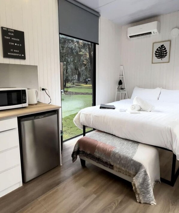 Ein Schlafzimmer mit einem Bett, einem Schreibtisch, einer Mikrowelle und einem kleinen Kühlschrank.