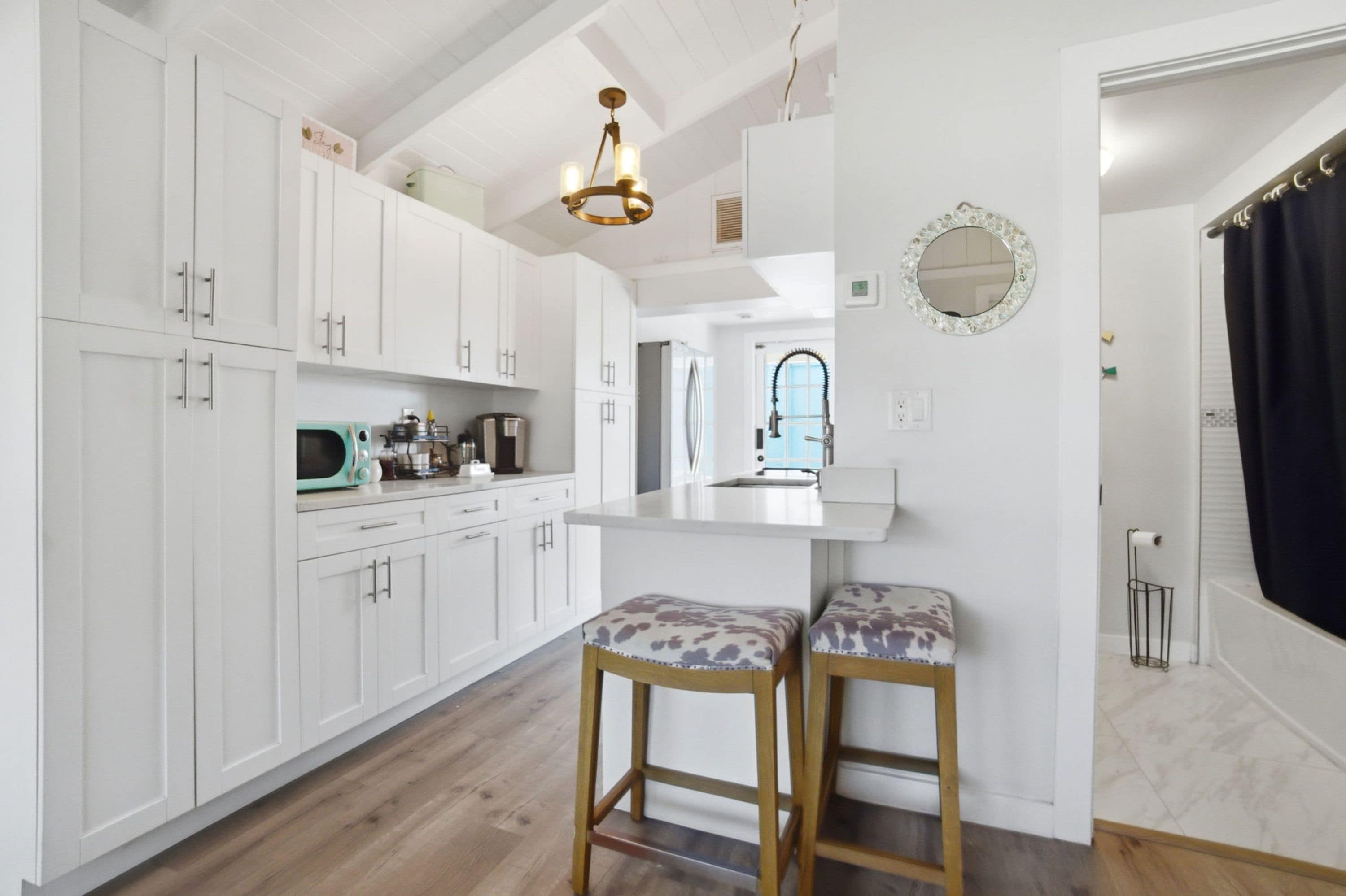 Una cocina moderna con armarios blancos, un banco de madera y una lámpara colgante.