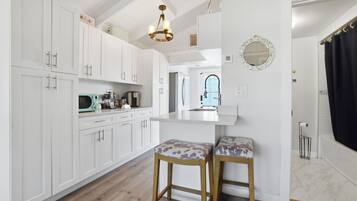 Una cocina moderna con armarios blancos, un banco de madera y una lámpara colgante.