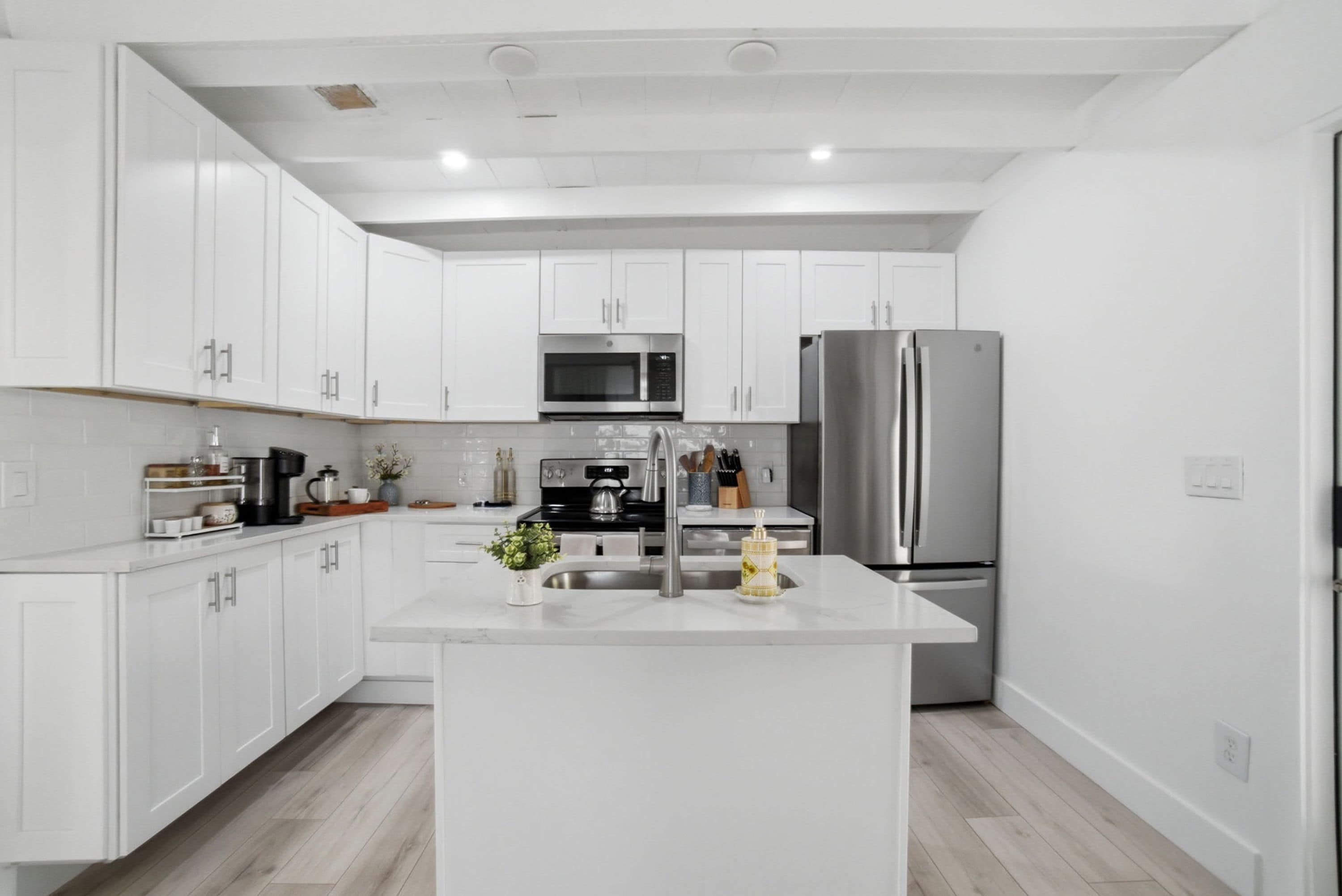 A modern kitchen with white cabinetry, stainless steel appliances, and a central island.