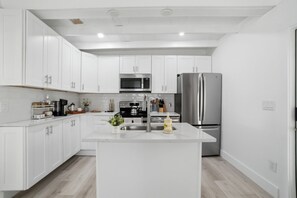 Una cocina moderna con armarios blancos, electrodomésticos de acero inoxidable y una isla central.