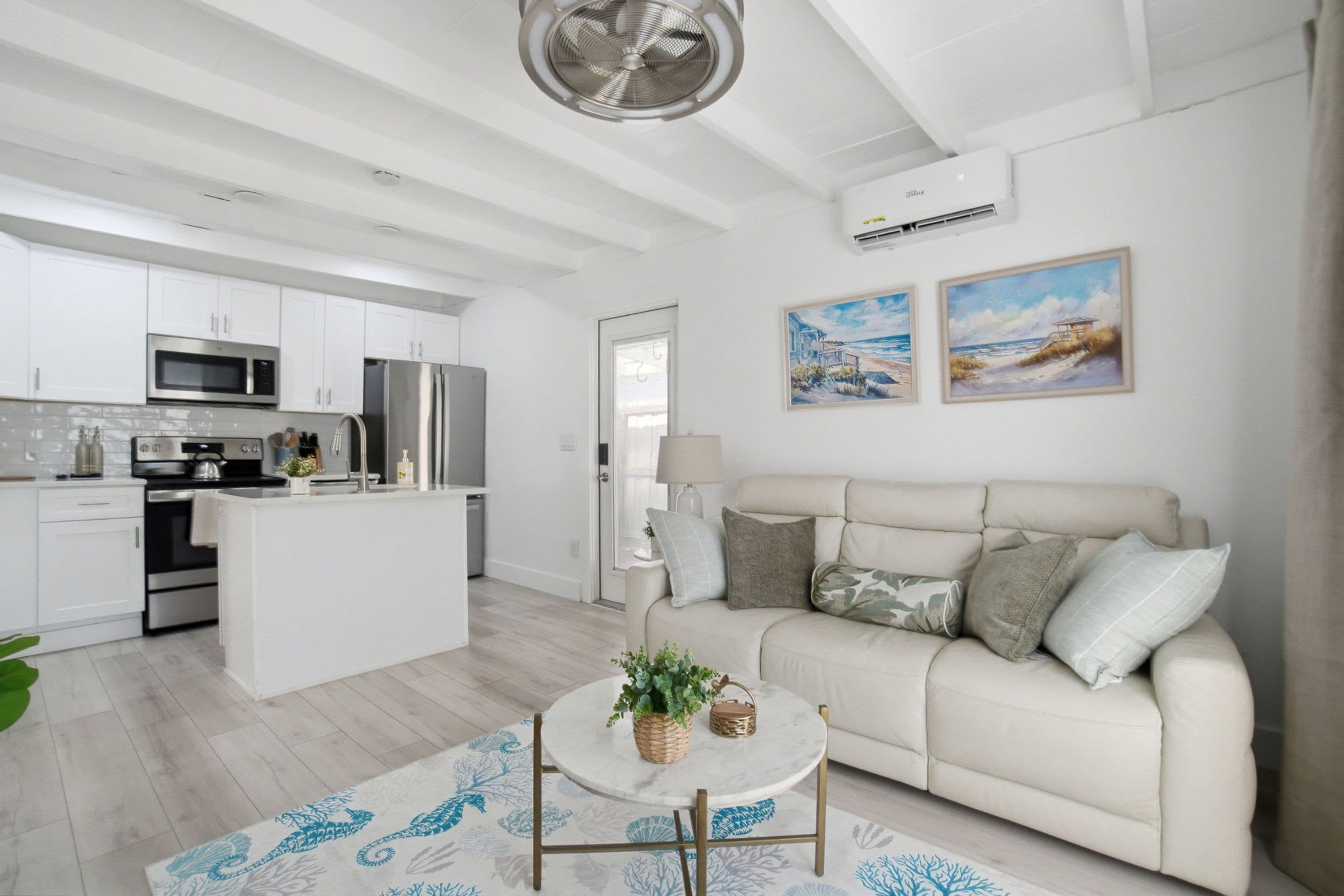 Una cocina moderna con armarios blancos, electrodomésticos de acero inoxidable y una isla central.