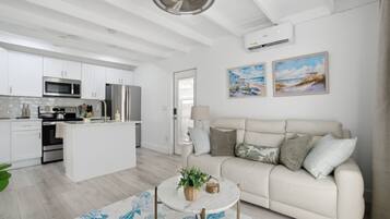 Una cocina moderna con armarios blancos, electrodomésticos de acero inoxidable y una isla central.
