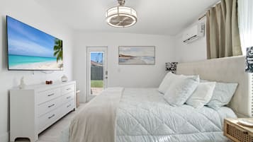Un dormitorio con cama, cómoda, televisión y obras de arte en las paredes.