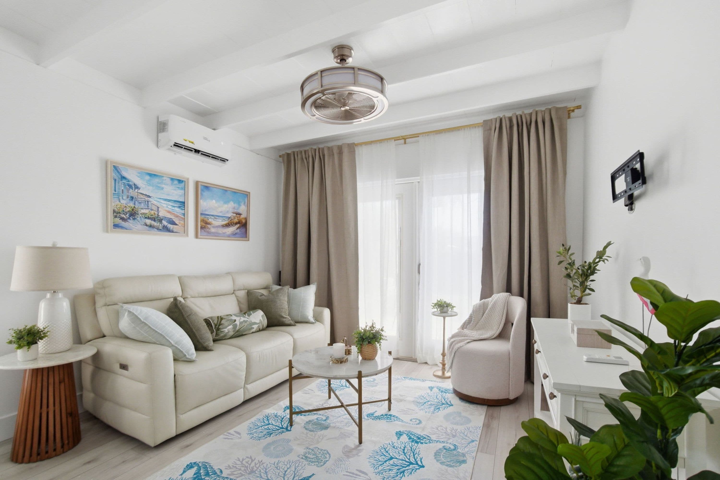 A modern living room with a sofa, coffee table, and a chair. There is a lamp, a small table with a plant, and a white cabinet.