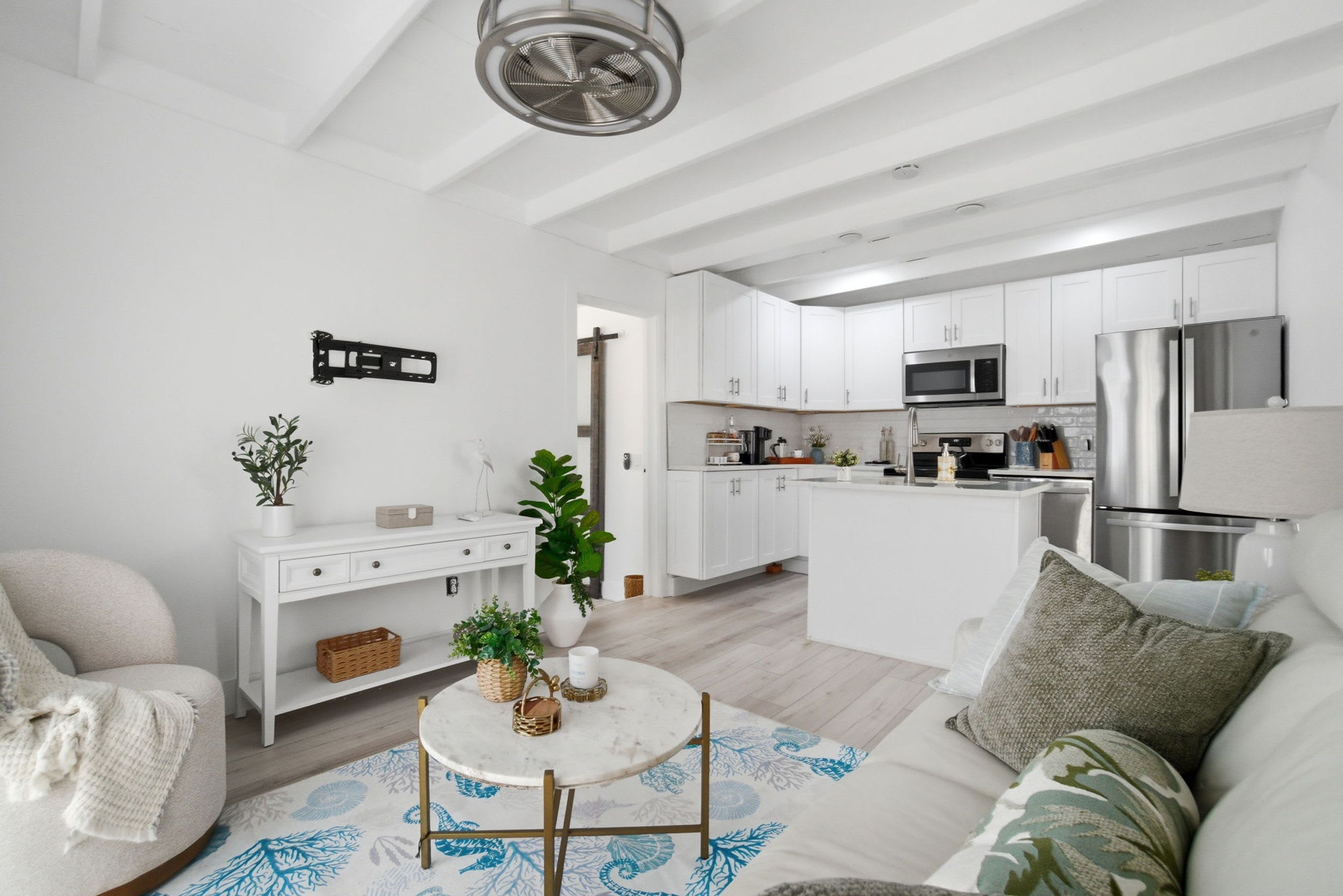 A modern kitchen with white cabinets, stainless steel appliances, and a central island.