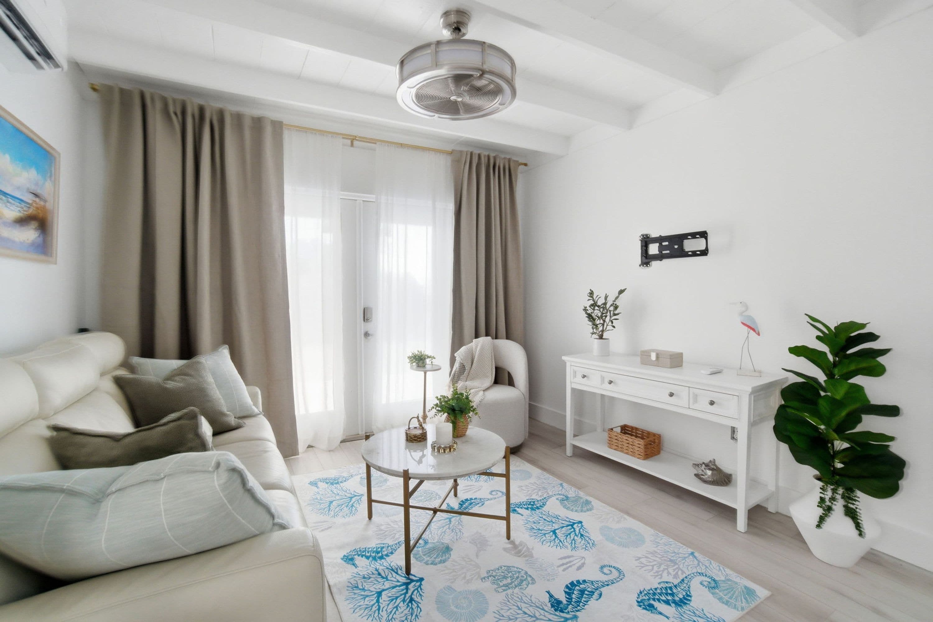 A modern living room with a sofa, a small round table, a white console table, and a large potted plant.