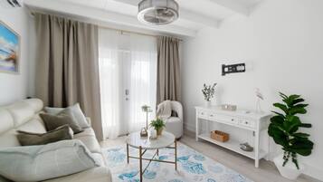 A modern living room with a sofa, a small round table, a white console table, and a large potted plant.
