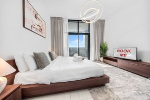 Ein modernes Schlafzimmer mit einem großen Bett, einem Fernseher und einem Schild mit der Aufschrift 'BOOK ME'.