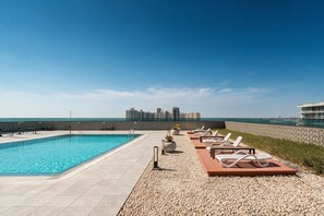 Ein Pool auf dem Dach mit Liegestühlen und Blick auf die Stadt.