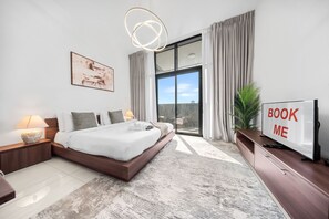 Ein modernes Hotelzimmer mit einem großen Bett, einem Flachbildfernseher, einem Schreibtisch und Blick ins Freie.