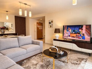 Un salon moderne avec un canapé gris, un téléviseur à écran plat, une table basse et une lampe décorative.