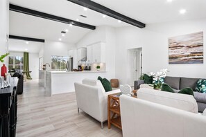 A modern living room with a sofa, a dining table, and a kitchen area in the background. - Naples Pool Home 10 Min to Naples Zoo (Naples)