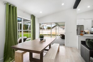 A modern kitchen with a dining area, large windows, and a view of a pool and house. - Naples Pool Home 10 Min to Naples Zoo (Naples)