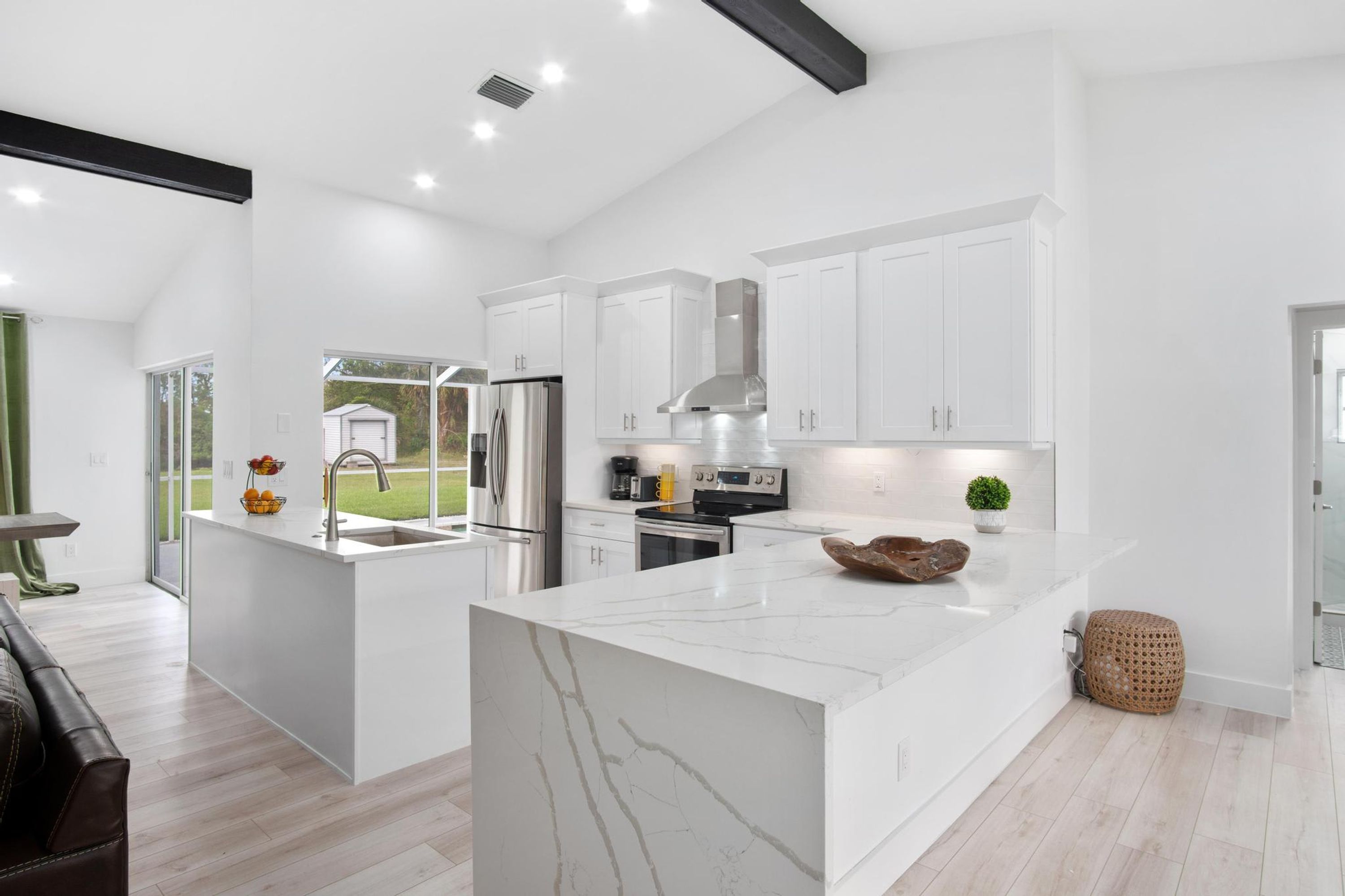 A modern kitchen with white cabinetry, a marble island, and stainless steel appliances.